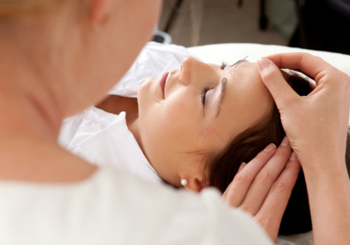 professional acupuncturist placing needle in face of patient